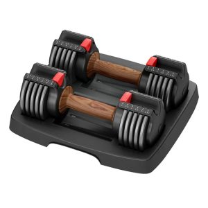 Pair of black and grey adjustable dumbbells with smooth wood-grain handles resting on a compact black storage tray, featuring a red quick-select weight adjustment slider.