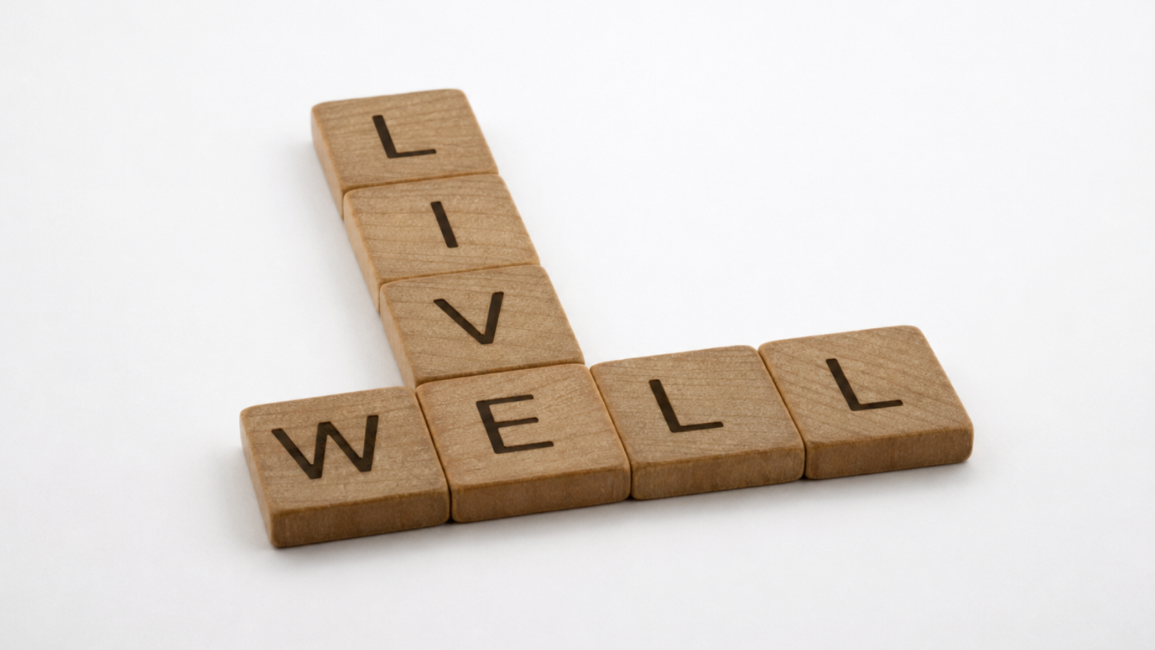 puraplace-pulse-post-feature-image-puraplace-welcome Wooden letter tiles arranged in a crossword to spell “Live Well” on a clean white background, representing healthy living and everyday wellness.