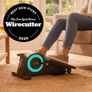 Person using a black Cubii Mini under desk elliptical with turquoise accent flywheel while seated indoors, promoting circulation, mobility, and low-impact fitness training. Badge noting New York Times 2026 Best New Picks