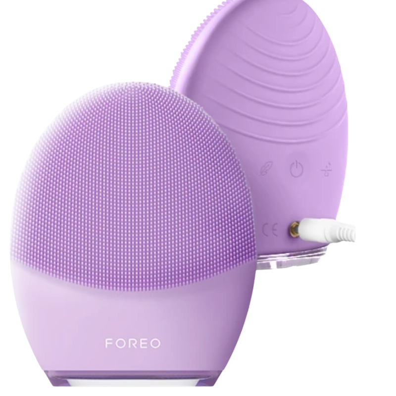 Front and back view of the FOREO LUNA 4 smart facial brush in Lavender for sensitive skin, showing the front cleansing bristles and the reverse side ridges with a plugged-in charging cable.